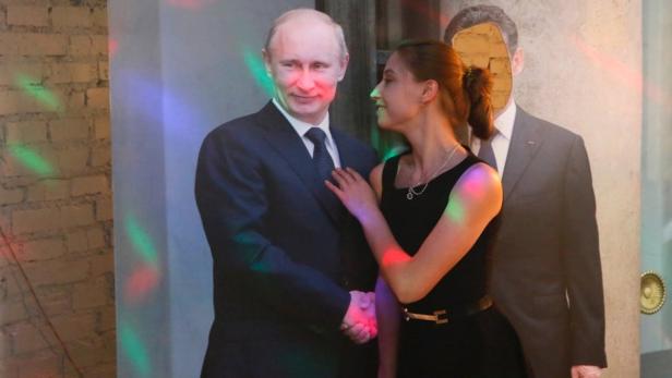 Eine Frau posiert mit einer Pappe von Wladimir Putin für ein Foto.