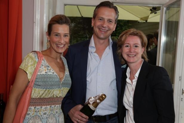 Drei Personen posieren mit einer Champagnerflasche für ein Foto.