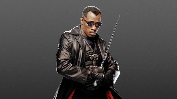 Wesley Snipes als Blade mit Sonnenbrille und Schwert vor grauem Hintergrund.