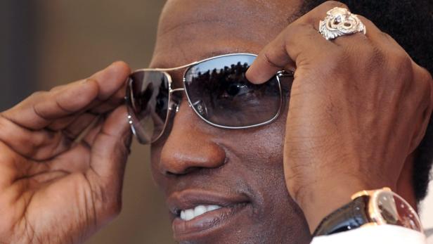 Ein Mann mit Sonnenbrille, auffälligem Ring und Armbanduhr.