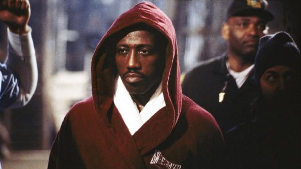 Wesley Snipes in einem roten Bademantel mit Kapuze, umgeben von Menschen.