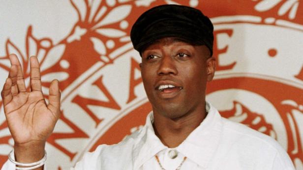 Wesley Snipes bei einer Veranstaltung mit erhobener Hand.