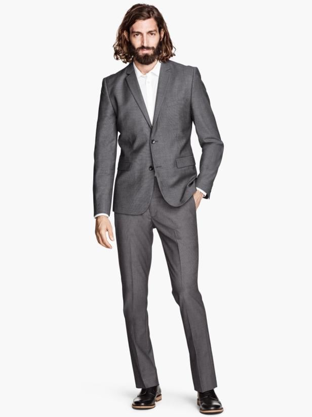 Ein Mann mit Bart und langen Haaren trägt einen grauen Anzug.