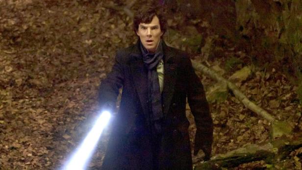 Benedict Cumberbatch als Sherlock Holmes mit einer Taschenlampe in einem dunklen Wald.
