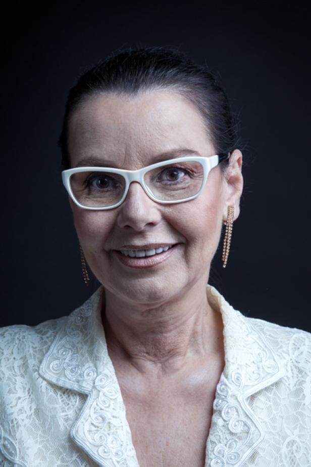 Eine Frau mit Brille und Ohrringen lächelt in die Kamera.