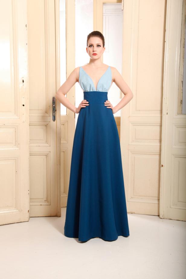 Eine Frau in einem langen, blau-hellblauen Kleid posiert vor einer Tür.