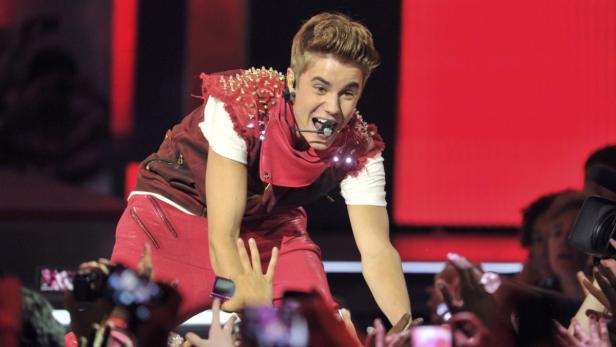 Justin Bieber tritt in roter Kleidung vor einer jubelnden Menge auf.
