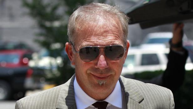 Ein Mann mit Sonnenbrille und Anzug lächelt in die Kamera.