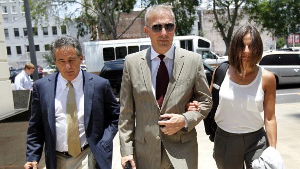 Kevin Costner wird von zwei Personen flankiert, während er ein Gerichtsgebäude verlässt.