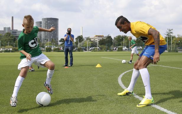 Ein Junge und ein Mann spielen Fußball auf einem grünen Rasenplatz.