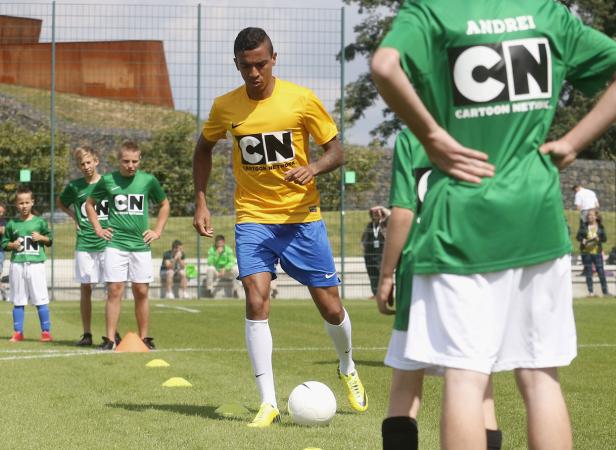 Ein Fußballspieler in gelbem Trikot dribbelt einen Ball auf einem grünen Rasen.