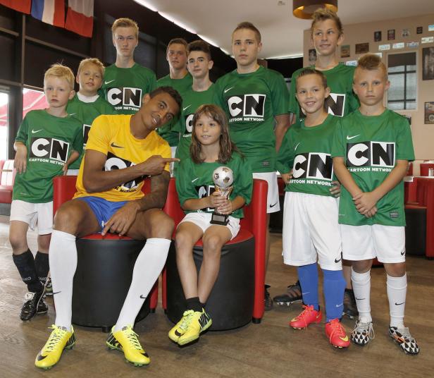 Eine Gruppe junger Fußballspieler mit einem Trainer und einem Mädchen mit einem Pokal.