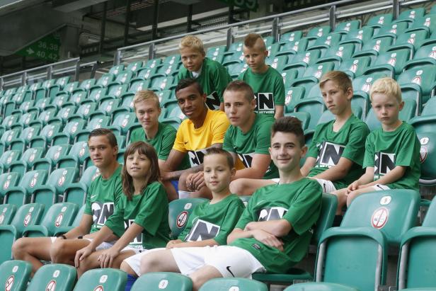 Eine Gruppe Jugendlicher sitzt auf der Tribüne eines Stadions.