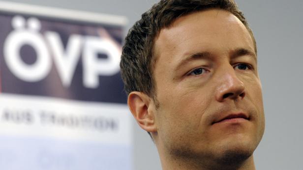 Ein Porträt eines Mannes vor einem verschwommenen ÖVP-Logo.