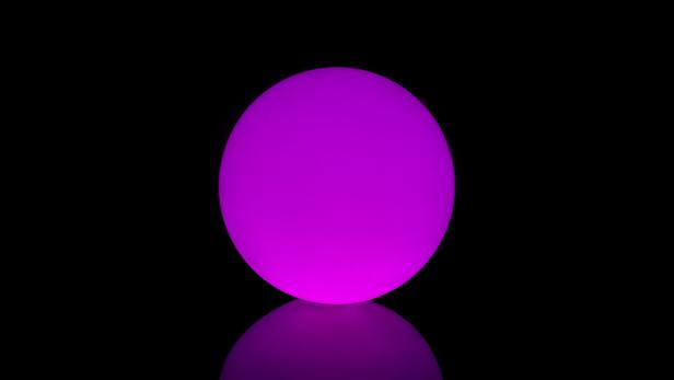 Eine leuchtend violette Kugel auf einer glänzenden, schwarzen Oberfläche.