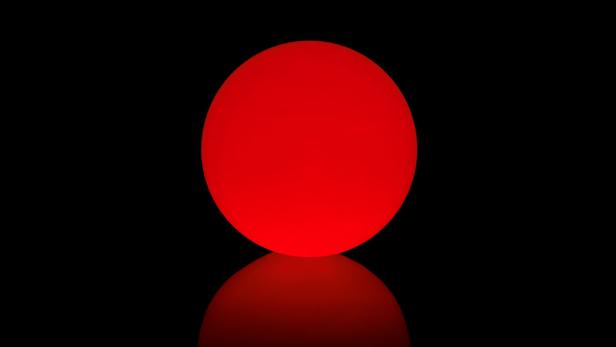 Eine rote Kugel auf einem schwarzen Hintergrund mit Spiegelung.