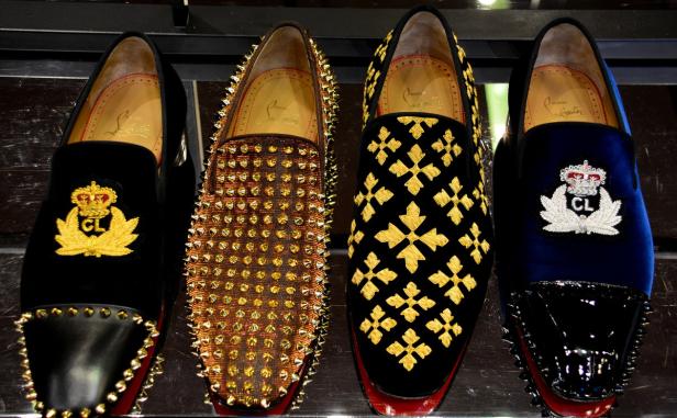 Vier Paar Louboutin-Slipper mit verschiedenen Verzierungen stehen nebeneinander.