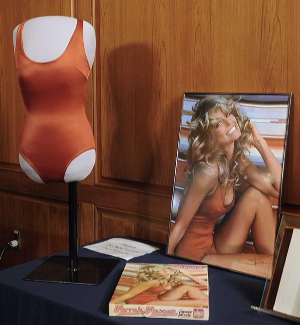 Ein Farrah Fawcett Badeanzug neben einem gerahmten Bild und einem Puzzle der Schauspielerin.