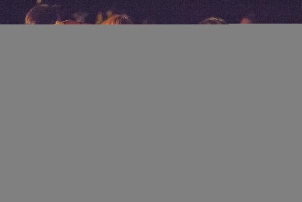 Menschen stehen im Dunkeln und schauen zu einer Aufführung.