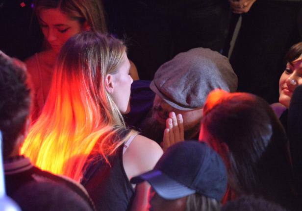 Leonardo DiCaprio flüstert einer Frau etwas ins Ohr.