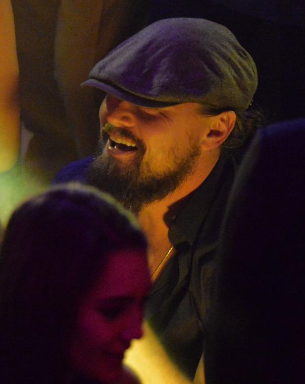 Leonardo DiCaprio lacht und trägt eine Schiebermütze.