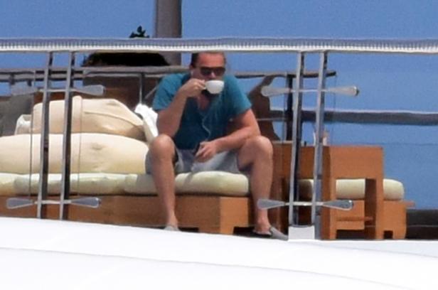 Leonardo DiCaprio sitzt auf einer Yacht und trinkt eine Tasse Kaffee.
