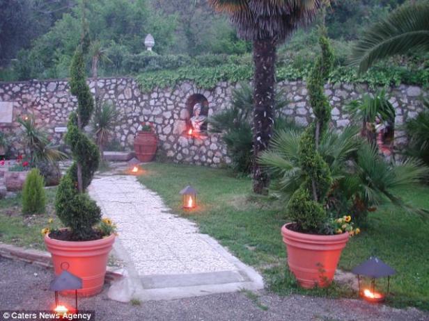 Ein Gartenweg ist mit Laternen und spiralgeschnittenen Bäumen geschmückt.