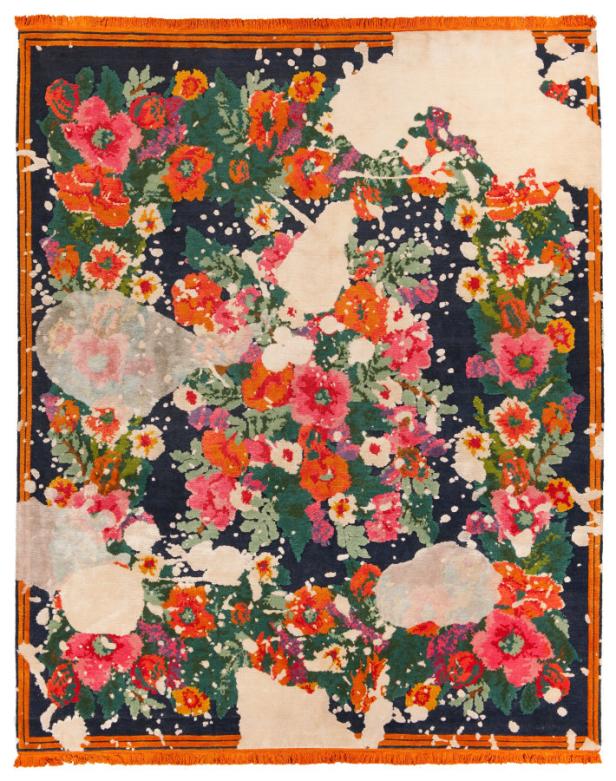 Ein Teppich mit einem floralen Muster in Rot-, Orange- und Grüntönen auf einem dunklen Hintergrund mit hellen Flecken.