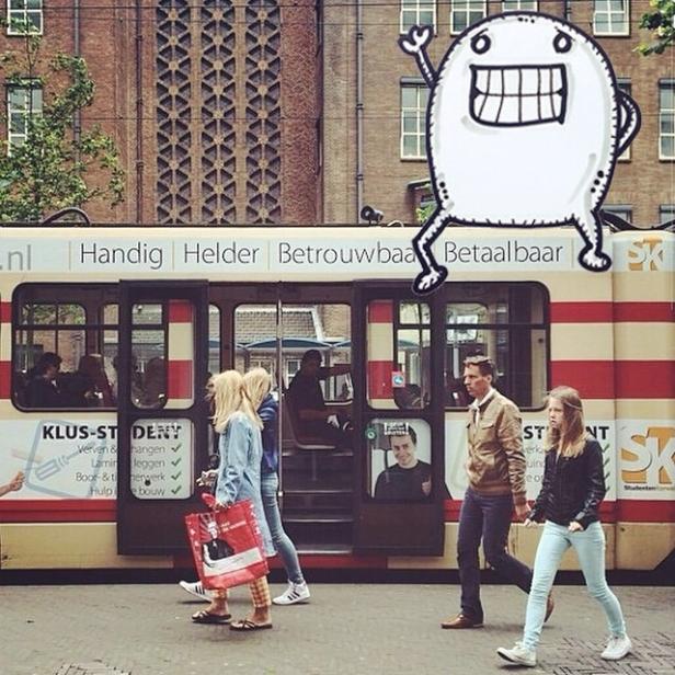 Menschen überqueren die Straße vor einer Straßenbahn mit einer Cartoon-Figur darauf.