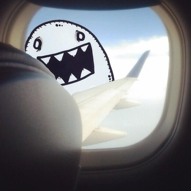 Ein gezeichnetes Monster schaut durch ein Flugzeugfenster.