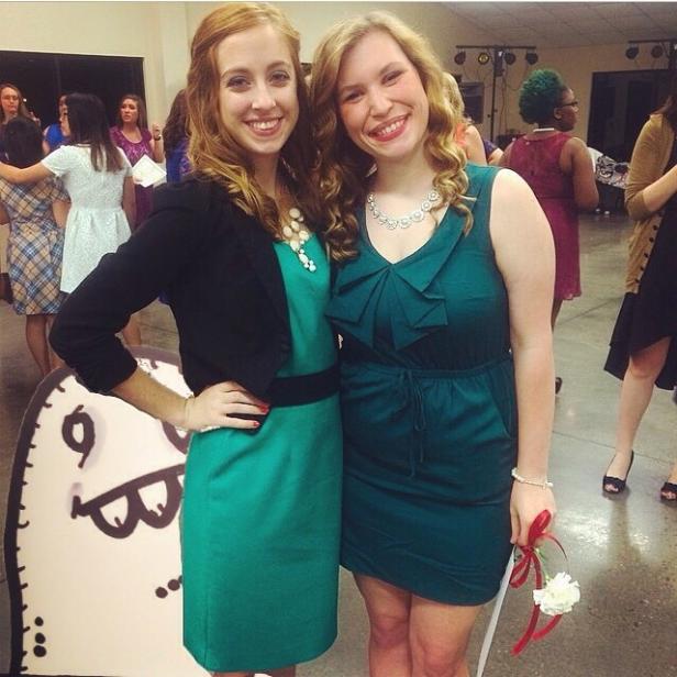 Zwei junge Frauen in grünen Kleidern posieren auf einer Party für ein Foto.