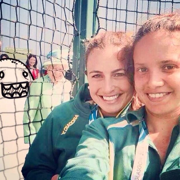 Zwei Sportlerinnen mit Medaillen machen ein Selfie; im Hintergrund ist Königin Elisabeth II. zu sehen.