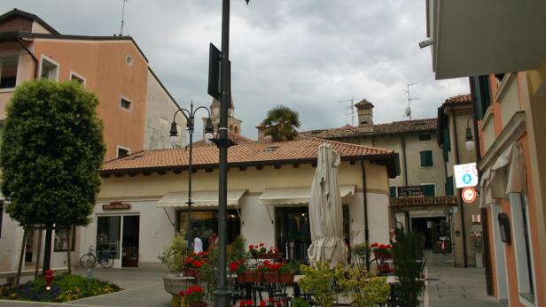 Ein belebter Platz in einer italienischen Stadt mit Geschäften und Restaurants.