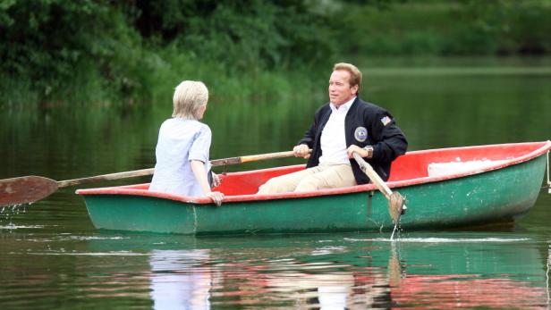 Arnold Schwarzenegger rudert mit einer Frau in einem kleinen Boot auf einem See.