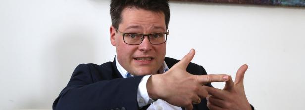 Ein Mann mit Brille gestikuliert mit seinen Händen.