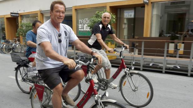 Arnold Schwarzenegger fährt mit dem Fahrrad durch die Stadt.