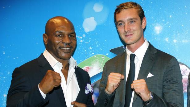 Mike Tyson und Pierre Casiraghi posieren mit geballten Fäusten vor einer Fotowand.
