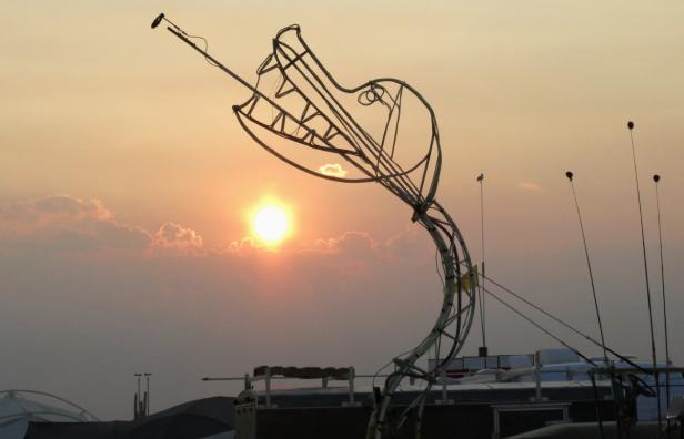 Eine metallene Krokodilskulptur vor einem Sonnenuntergang.
