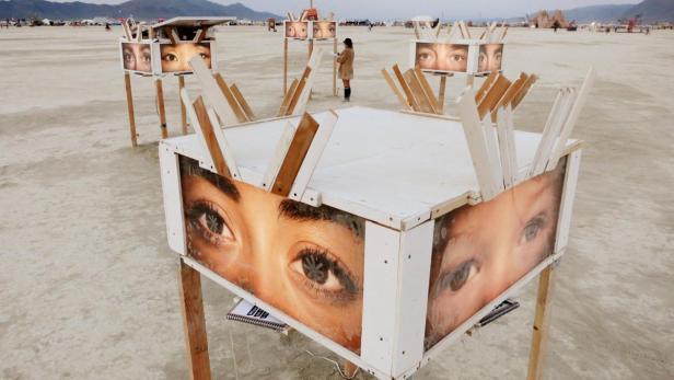 Eine Kunstinstallation mit Augenmotiven in der Wüste, vermutlich beim Burning Man Festival.