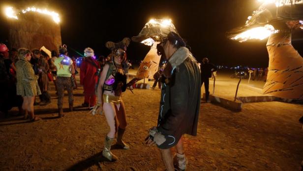 Menschen in Kostümen feiern auf dem Burning Man Festival bei Nacht.