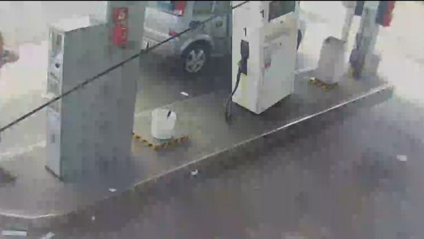 Eine Tankstelle mit Zapfsäulen und einem Auto im Hintergrund.