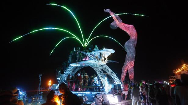 Eine beleuchtete Frauenskulptur und ein mehrstöckiges Kunstfahrzeug ziehen auf dem Burning Man Festival die Blicke auf sich.