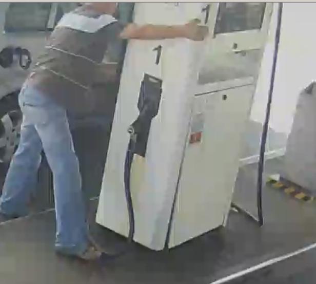 Ein Mann manipuliert eine Zapfsäule an einer Tankstelle.