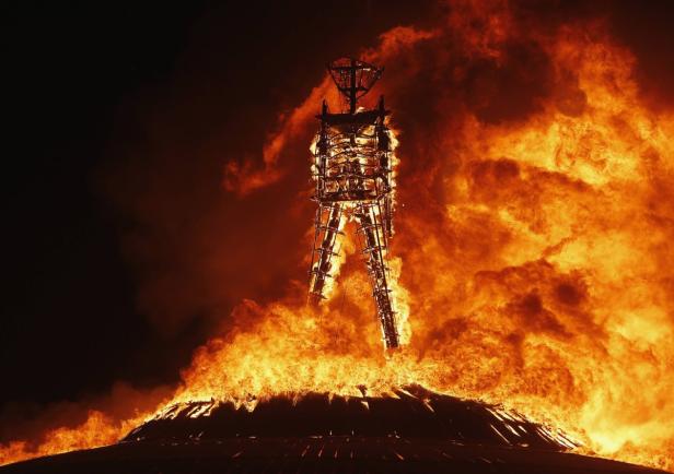 Eine große Holzfigur steht in Flammen, vermutlich während des Burning Man Festivals.