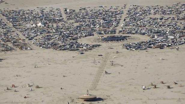 Luftaufnahme des Burning Man Festivals in der Wüste von Nevada mit zahlreichen Zelten und Installationen.