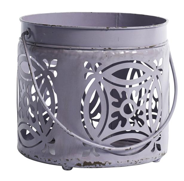 Ein lilafarbenes Windlicht aus Metall mit floralen Ausschnitten und einem Henkel.