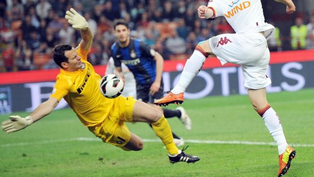 Ein Fußballspieler schießt den Ball, während der Torwart versucht, ihn abzuwehren.