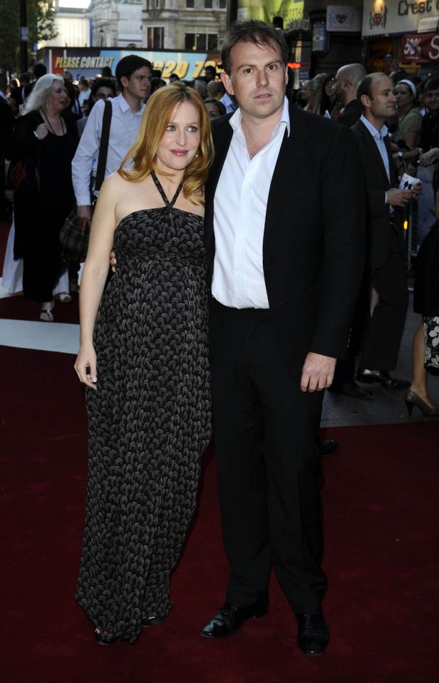 Gillian Anderson und ein Mann posieren auf einem roten Teppich.