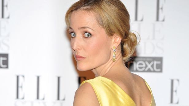 Gillian Anderson bei einer Veranstaltung im gelben Kleid und Ohrringen.