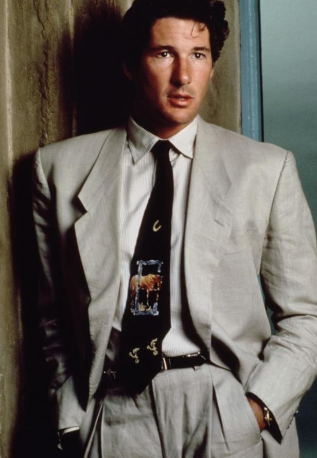 Richard Gere in einem hellen Anzug mit einer Krawatte mit Pferdemotiv.